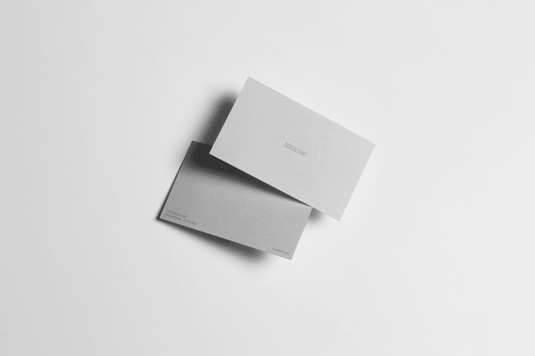 Two minimalist business cards overlapping on a white surface, both featuring "masse" branding in clean typography. The cards cast subtle shadows, emphasizing their simple, elegant design. by Sydney SG