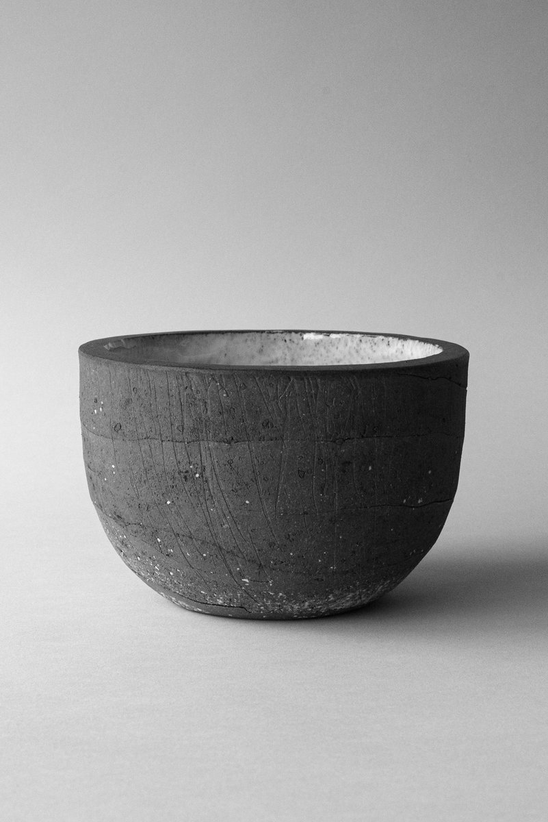 Stoneware bowl with a rough texture, centered in the frame against a soft, neutral background. by Sydney SG