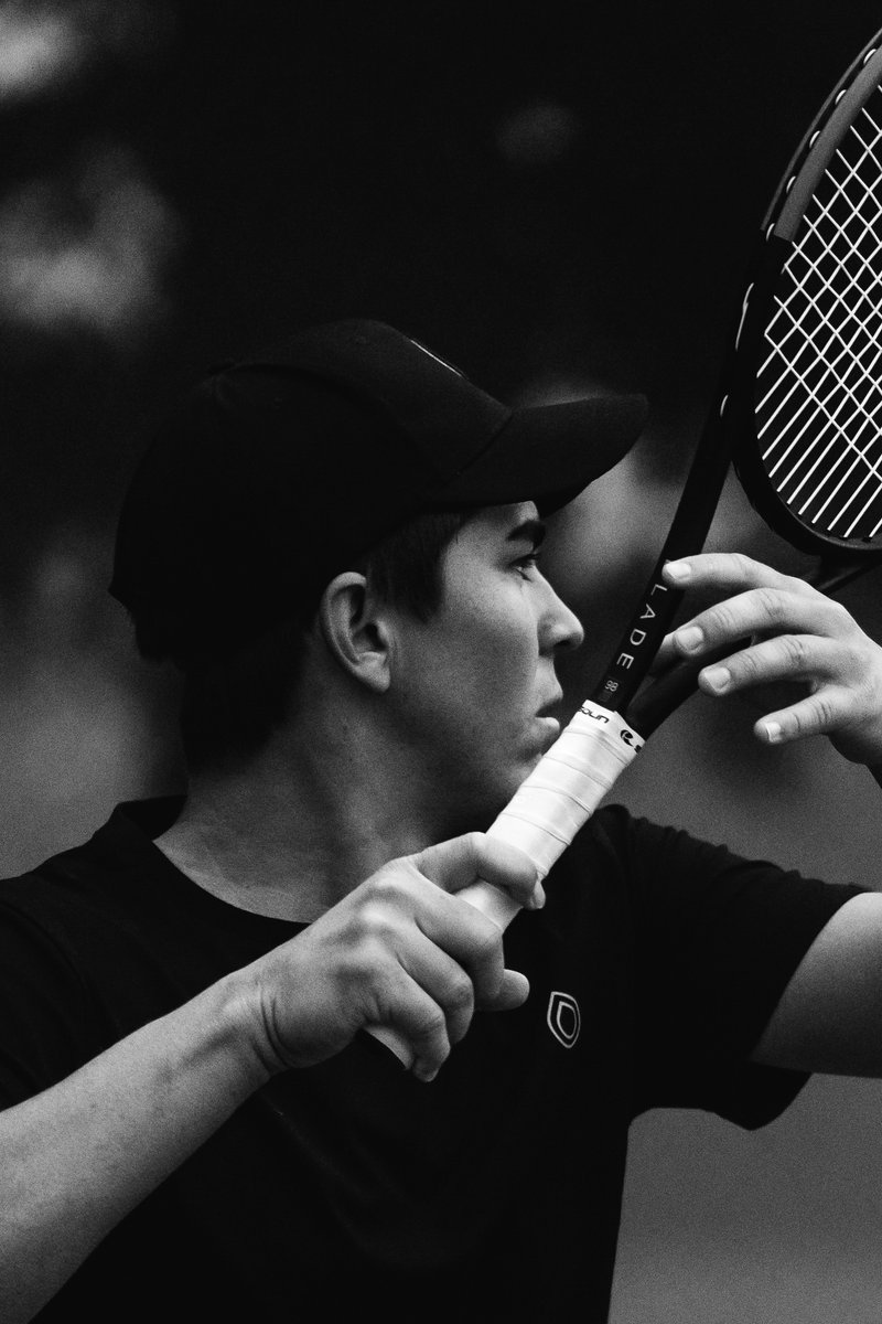 Tennis player in a black cap and shirt, preparing to swing a racket during a match. by Sydney SG