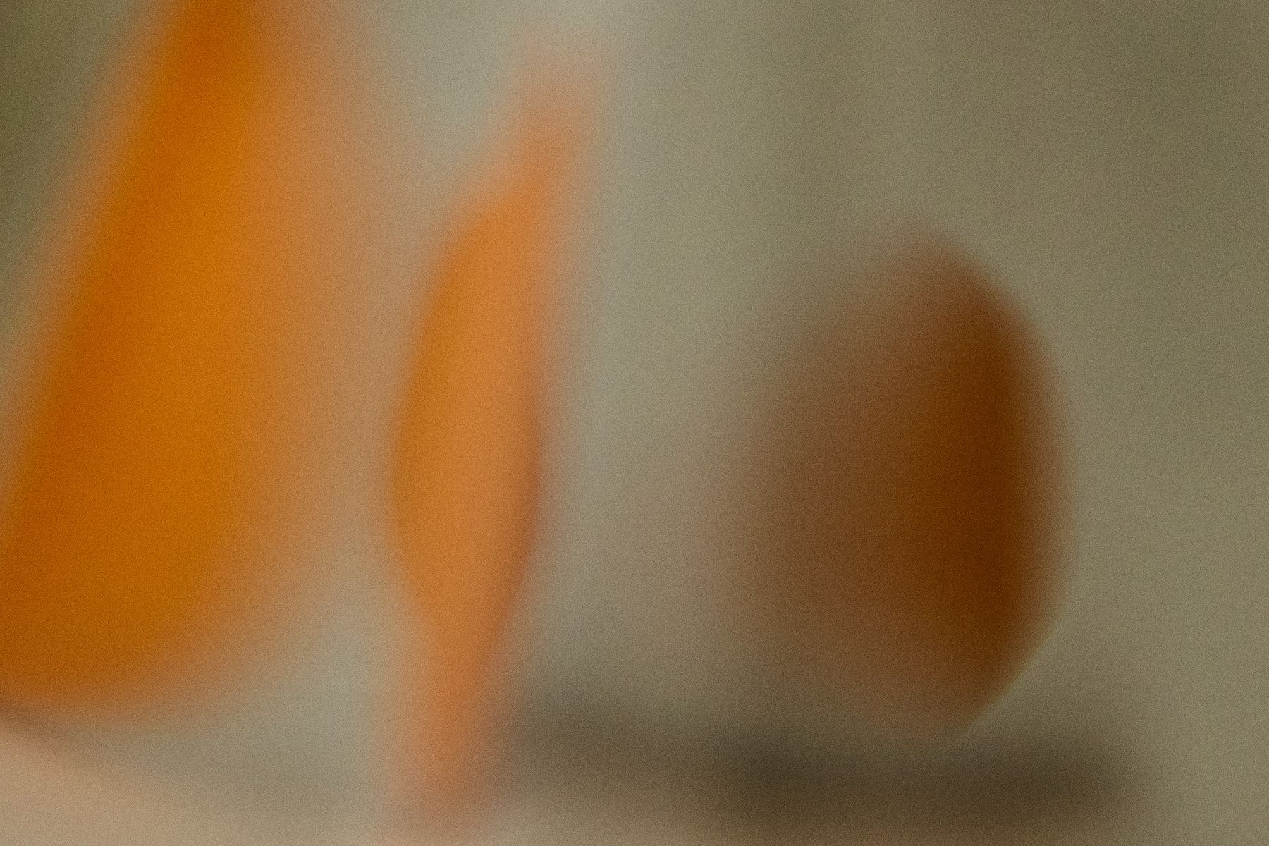 Abstract blur of warm orange tones against a cool sage green background. The intentional lack of focus transforms ordinary objects into pure color and form. by Sydney SG