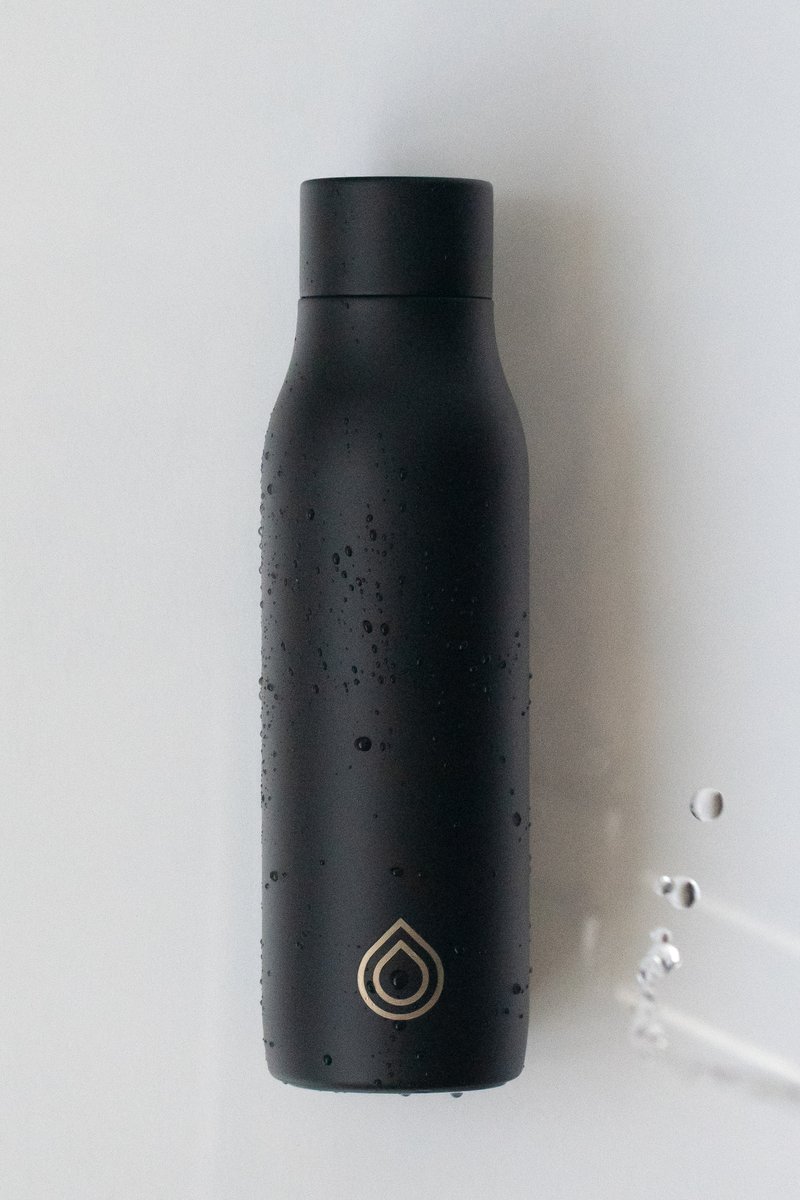 Black matte water bottle with droplets of water on it, resting on a flat surface with a minimalist logo. by Sydney SG