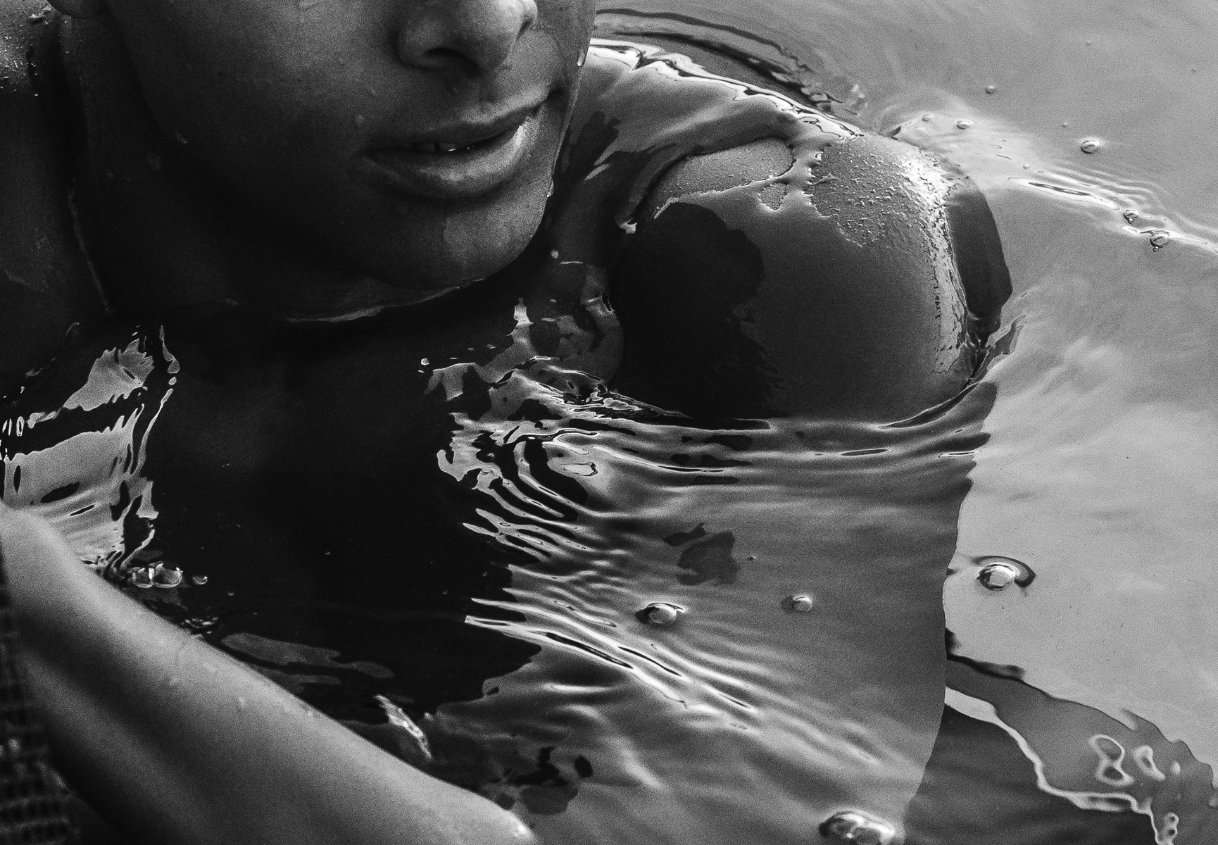 Close-up of a person submerged in water, focusing on the rippling surface and reflection of light. by Sydney SG