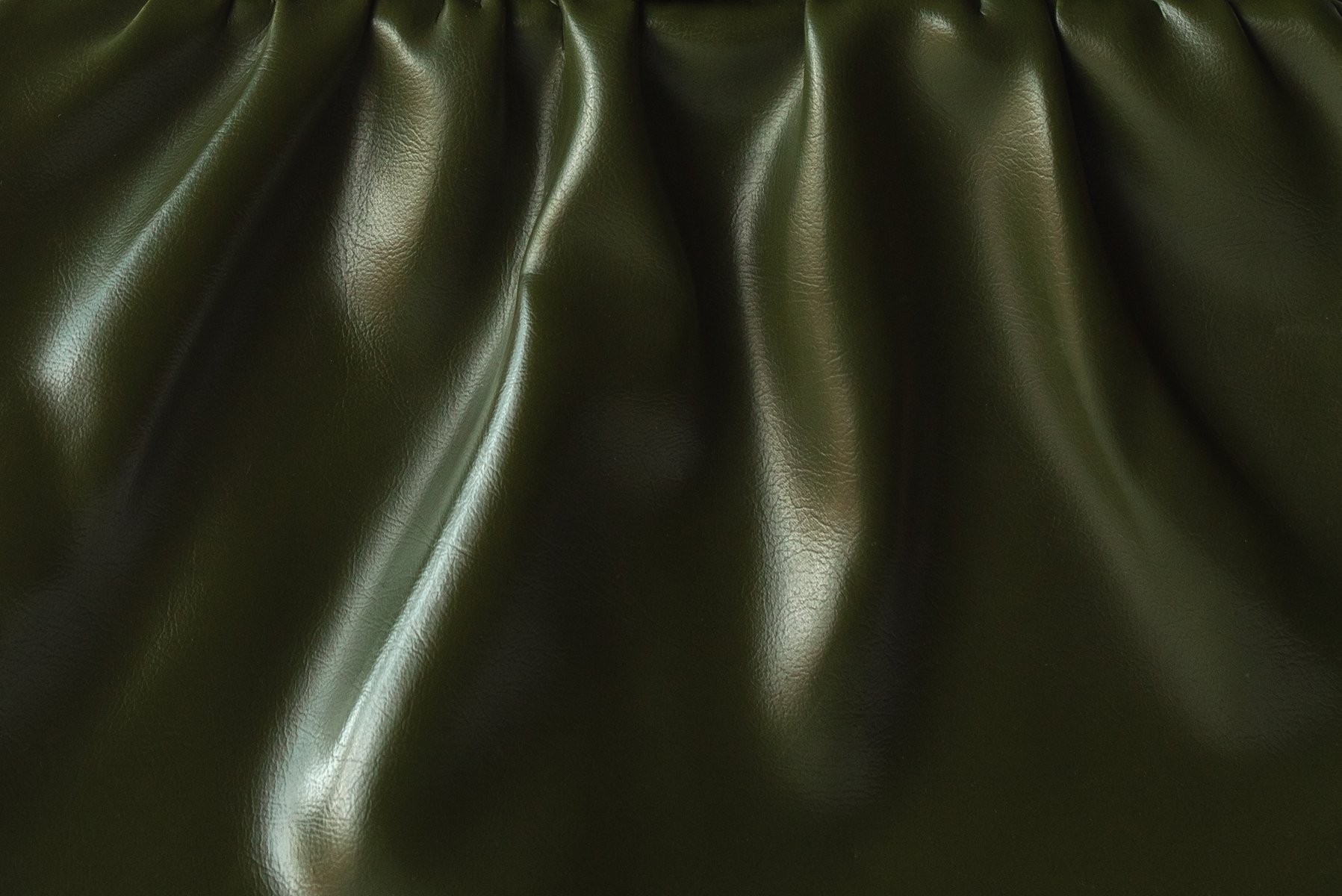 Close-up of textured, crumpled green leather, showcasing creases and highlights. by Sydney SG