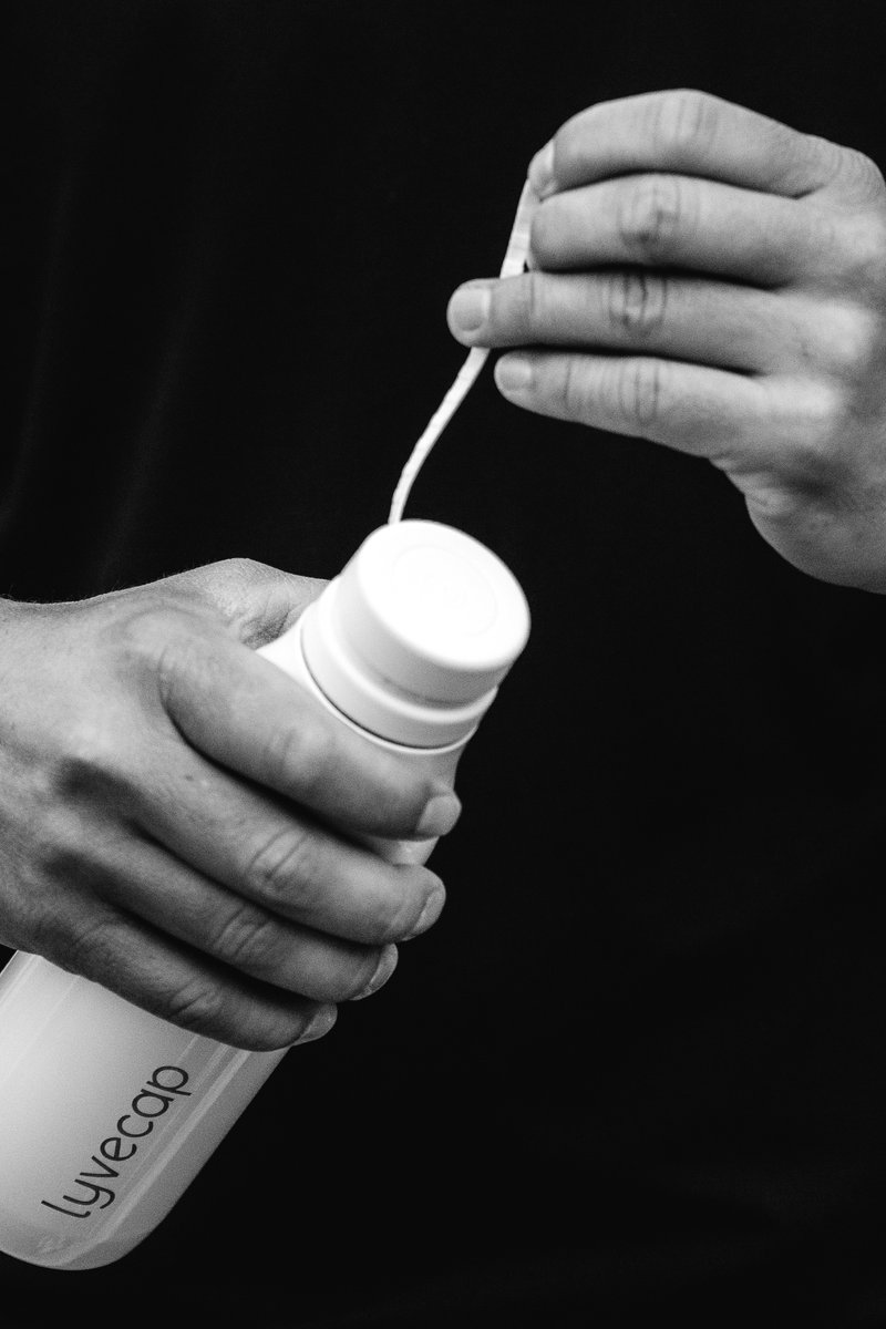 Close-up image of hands opening a white bottle cap. by Sydney SG