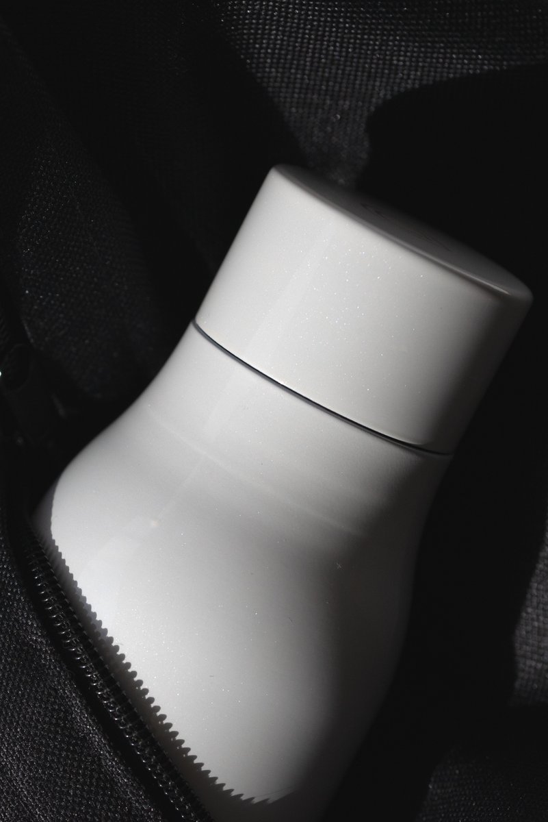 Close-up of a white bottle partially concealed in a black bag. by Sydney SG