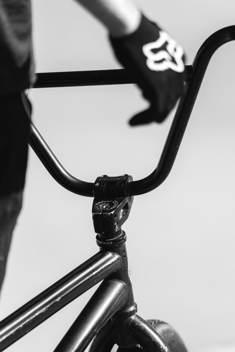 Black and white shot of a cyclist's hands holding the handlebars of a BMX bike. by Sydney SG