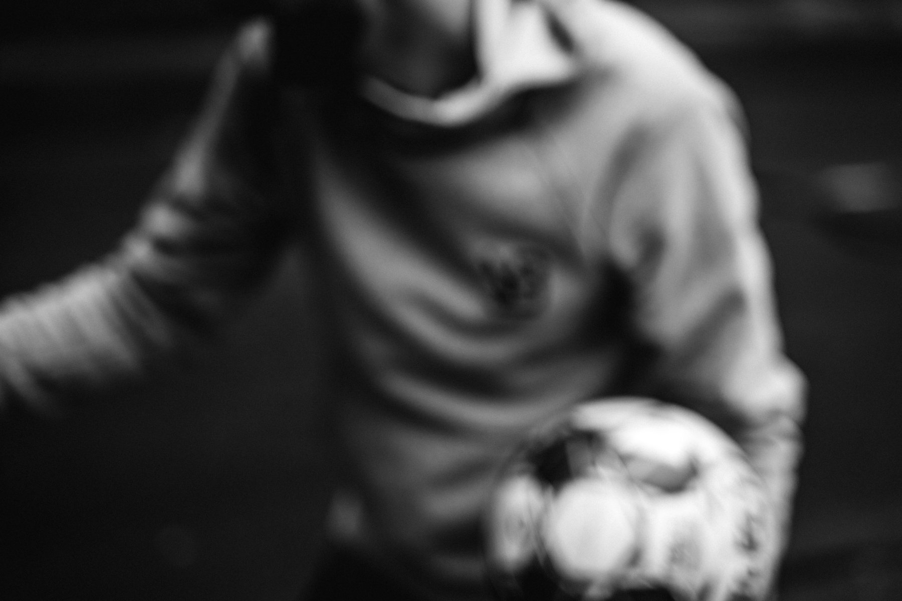 Blurred motion shot of a person in a hoodie holding a soccer ball. by Sydney SG