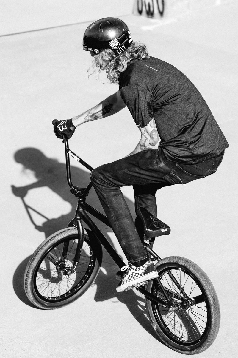 A BMX rider performing a trick on a bike in a skate park, shot in black and white. by Sydney SG