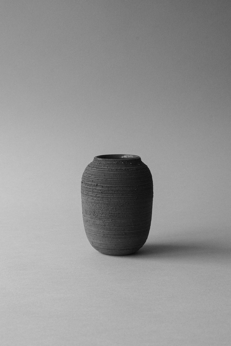 Dark, rounded stoneware vase with horizontal textured lines, centered on a plain background. by Sydney SG